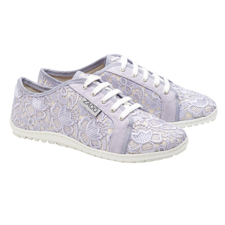 Ein Paar ZAQQ QELLY Purple Sneaker für Damen, in einem hellen Lila mit weißen Schnürsenkeln und Sohlen, verziert mit einem Blumenstickerei-Muster. Die Schuhe werden nebeneinander präsentiert und zeigen das ZAQQ-Label an der Seite.