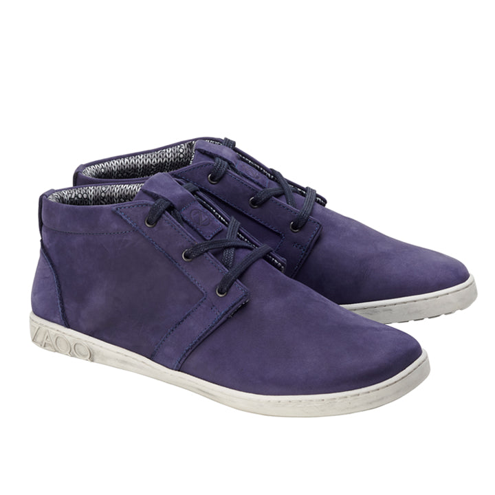 Der LANQASTER Navy von ZAQQ ist ein Paar lilafarbene Freizeitschuhe mit Schnürung, weißer Sohle und High-Top-Design. Diese Schuhe sind aus Veloursleder gefertigt, mit einem strukturierten Futter, das um den Knöchel herum sichtbar ist, und der Markenname ist seitlich auf der Sohle eingeprägt, was für noch mehr unverwechselbaren Reiz sorgt.