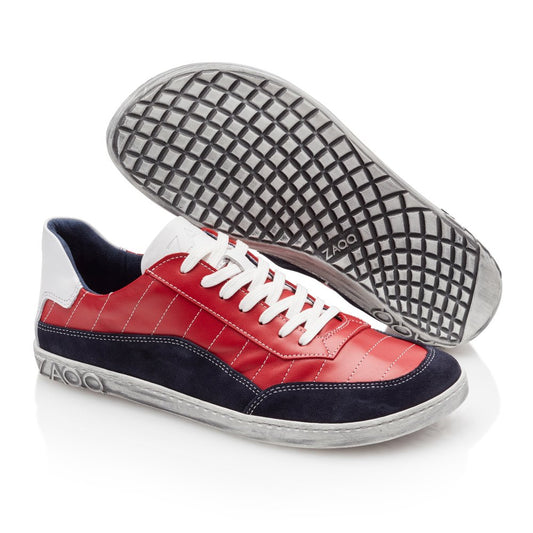 Die QAMPION Navy Red Sneaker von ZAQQ präsentieren ein stilvolles Design mit Obermaterial aus Nappaleder in einer auffälligen Kombination aus Rot und Marineblau, akzentuiert durch weiße Details und Schnürsenkel. Die Sohlen weisen Gittermuster auf, die den Komfort eines Barfußschuhs verkörpern. Das ZAQQ-Branding ist sowohl an der Ferse als auch an der Sohle deutlich zu sehen.