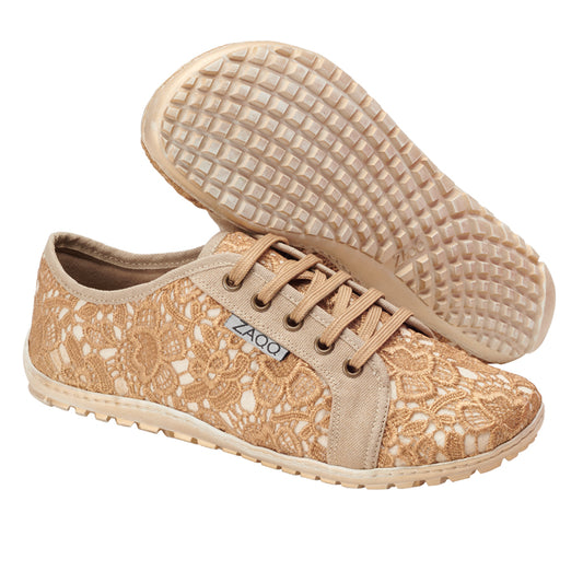 Wir präsentieren den QELLY Beige Gold von ZAQQ: Diese femininen Sneaker zeichnen sich durch ein elegantes Spitzenmuster mit gewebter Textur auf dem Obermaterial und braunen Gummisohlen aus. Sie verfügen über einen stilvollen Seitenstreifen, ein klassisches Schnürdesign und zeigen stolz den Markennamen ZAQQ auf einer Seite.