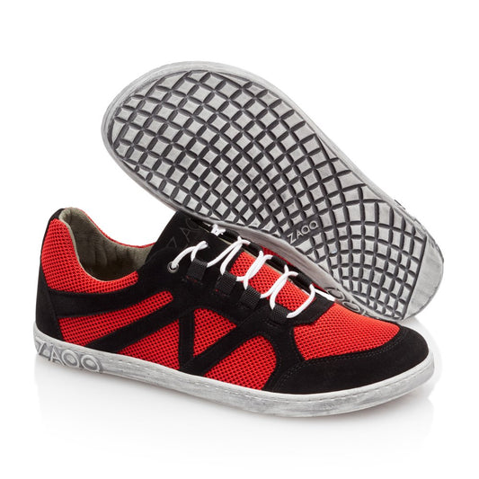 Wir präsentieren den QUSQO Red von ZAQQ, ein stilvolles Paar Freizeit-Sneaker, ideal für Laufbegeisterte. Diese Sneaker verfügen über rotes Mesh und schwarze Wildlederauflagen, ergänzt durch weiße Schnürsenkel und eine gemusterte weiße Sohle. Das ikonische ZAQQ-Branding ist auf der Ferse dieser modischen Schuhe sichtbar. Ein Schuh steht aufrecht, während der andere auf der Seite liegt.