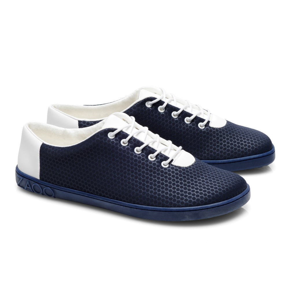 Wir präsentieren den QARO Mare von ZAQQ: ein Paar Sneaker in Marineblau und Weiß, hergestellt aus veganen Materialien und mit sechseckigen Mustern auf dem Stoff. Diese stylischen Schuhe haben weiße Schnürsenkel, die weiße Absätze ergänzen, und eine leuchtend blaue Sohle.