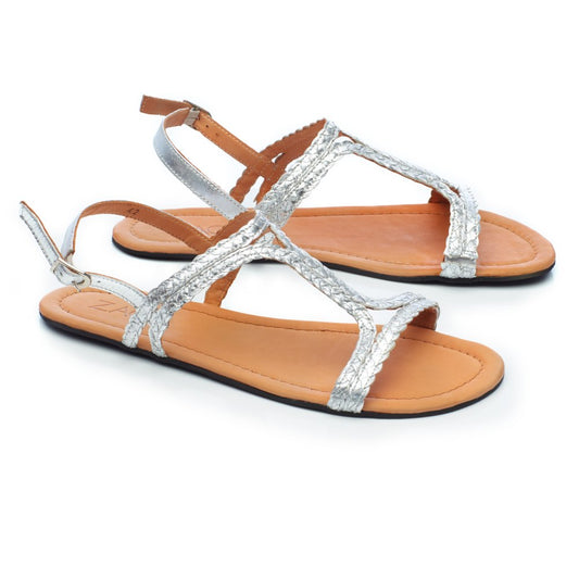 Entdecken Sie die QOSTA Silver Damensandalen von ZAQQ, ideal für die Sommermode. Das Design mit strukturierten silbernen Riemen und hellbraunen Sohlen verfügt über eine Schlaufe für den großen Zeh und einen verstellbaren Knöchelriemen. Diese von Barfuß-Sandalen inspirierten Schuhe haben flache, schwarze Laufsohlen und sorgen die ganze Saison über für Stil und Komfort.